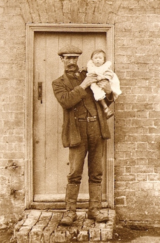 John Pope holding his daughter Audrey outside their home at 239 Main Street, Witchford, circa 1921.